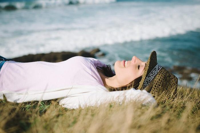 women lays on grass near the ocean